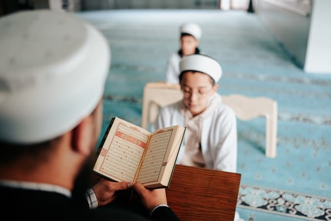 Young Muslim boy reciting Holy Quran with certified teacher in a mosque